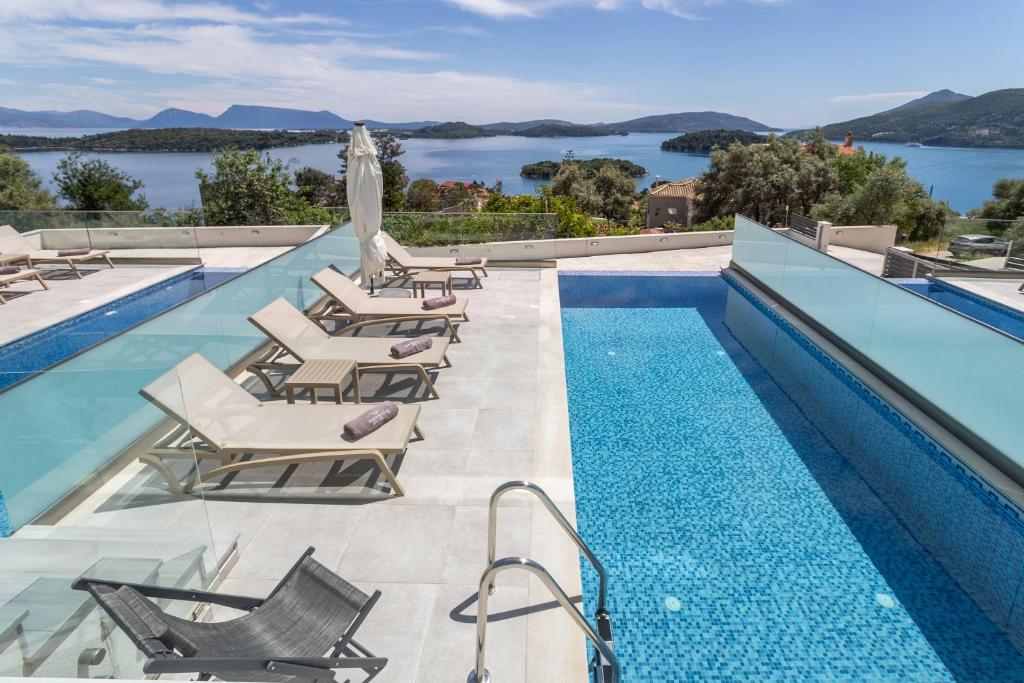 a swimming pool with lounge chairs and a view of the water at Diamond Blue Villas Lefkada in Nydri