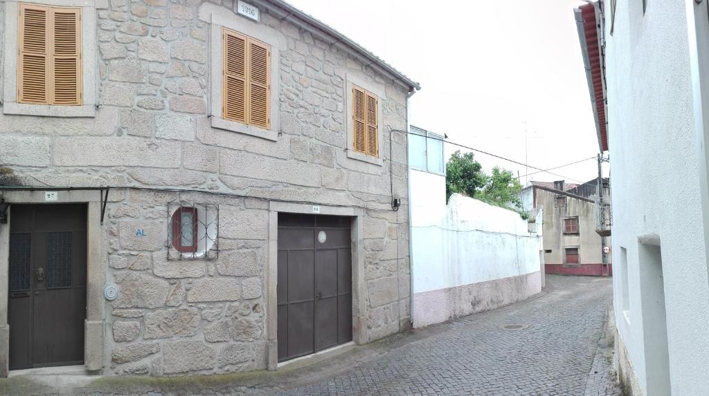 a stone building with two garage doors on a street at Casa da Rosa in Póvoa de Rio de Moinhos