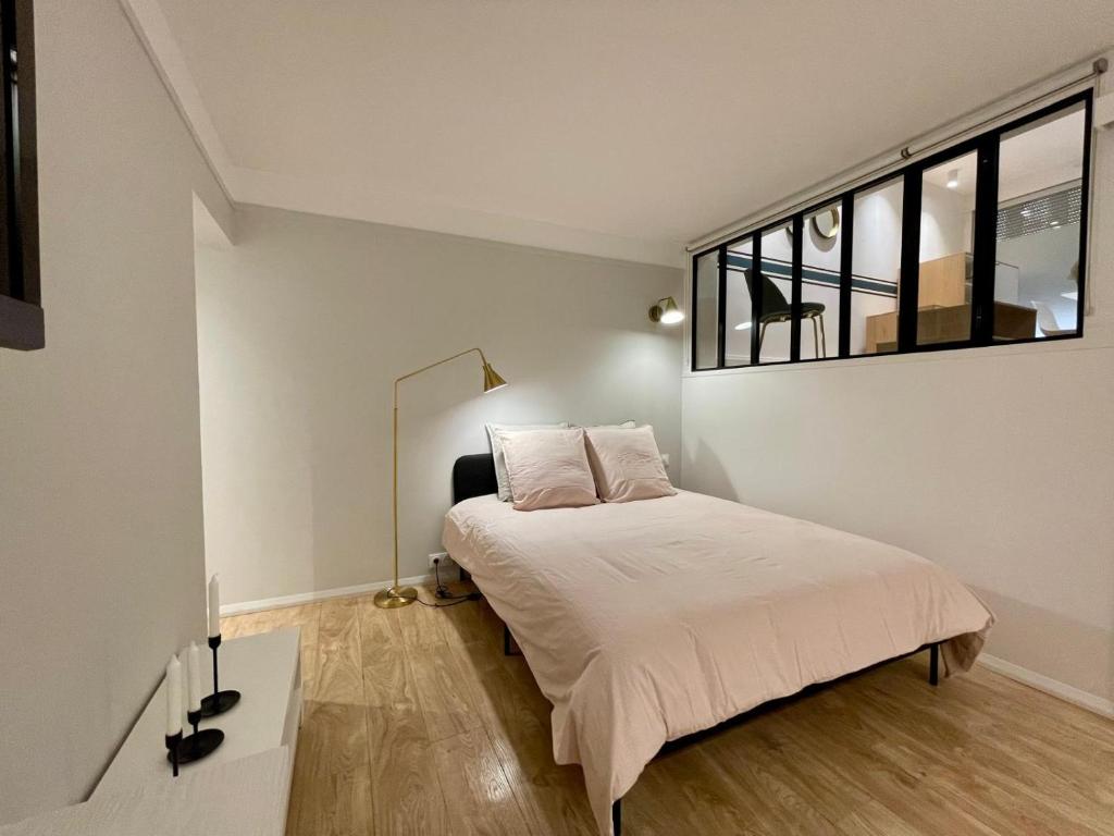 une chambre avec un lit avec des draps blancs et une fenêtre dans l'établissement Apt 4 Guests Moderne Place Breteuil, à Paris