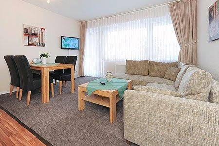 uma sala de estar com um sofá e uma mesa em Ferienwohnungen Alter Sielweg Wohnung 10 em Bensersiel