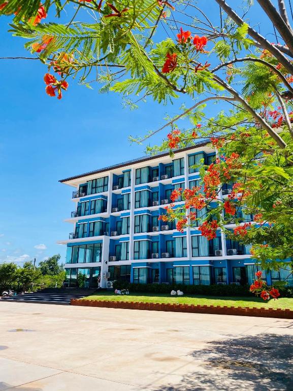 a large building with red flowers in front of it at Arunsakhon luxury condo in Ban Khok Kham