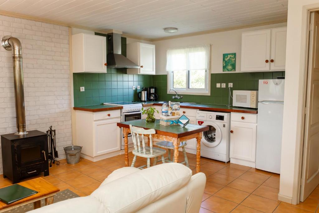 eine Küche mit weißen Schränken und einem Tisch und einem Herd in der Unterkunft Quinta das Acácias in Livramento