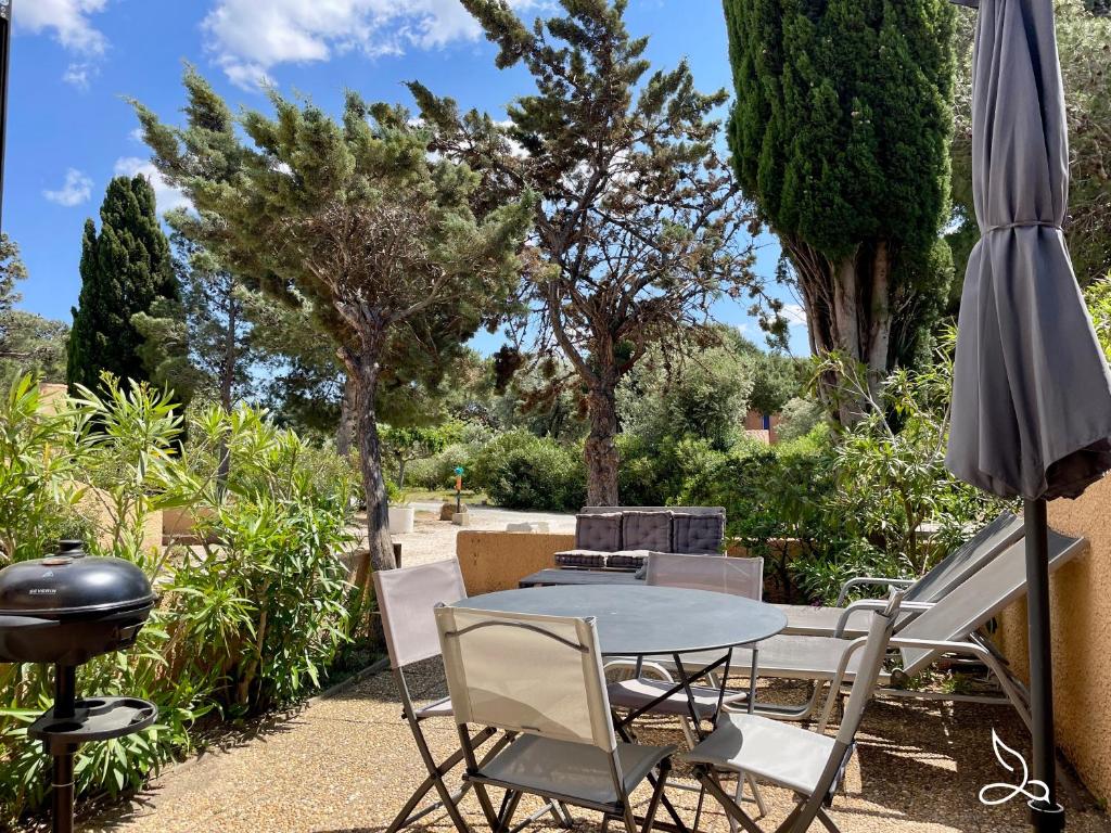un patio avec une table, des chaises et un parasol dans l'établissement Maison 5pers-clim-piscine-wifi, à Fitou