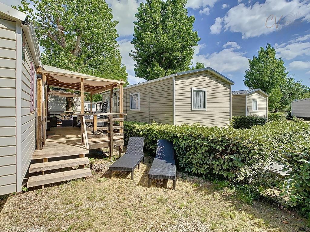 une arrière-cour avec deux bancs et une maison dans l'établissement Mobil-Home FO 49 à Vias - La Carabasse - Camping Siblu avec piscine, à Vias