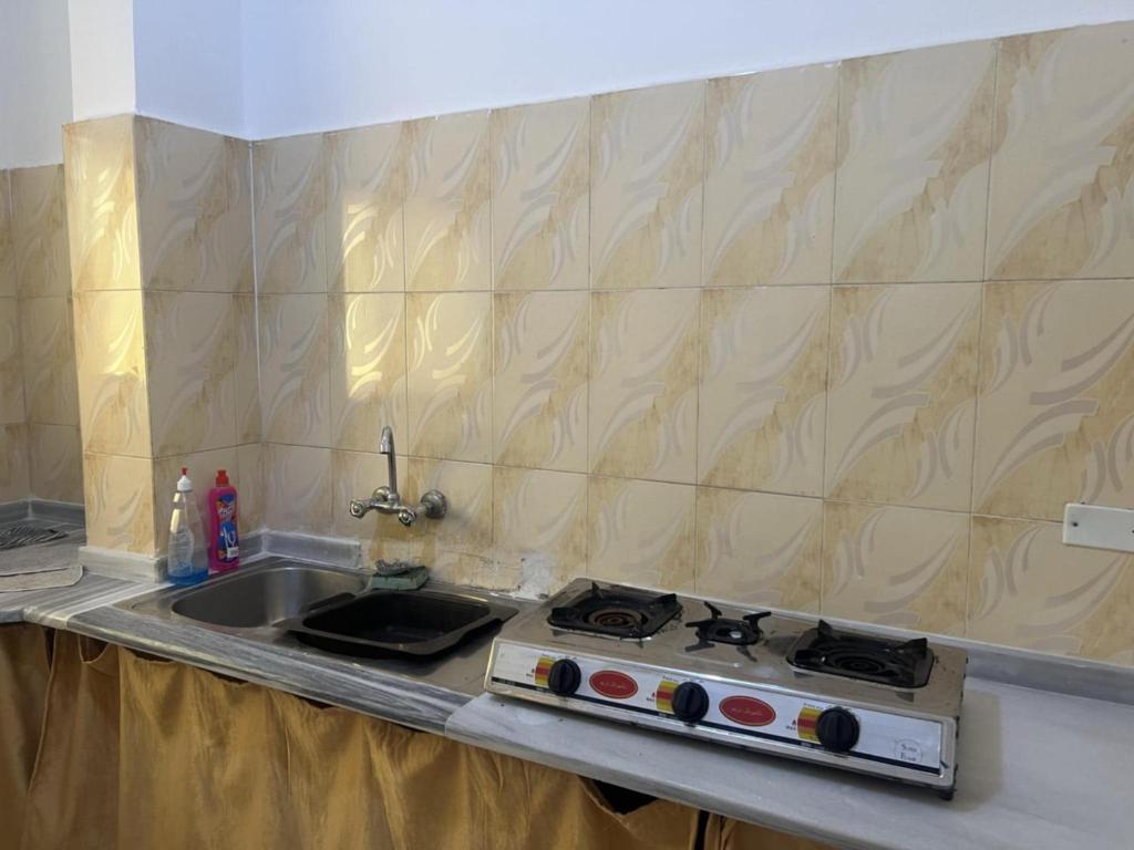 a kitchen counter with a stove and a sink at Altamem apartment in Um Qeis