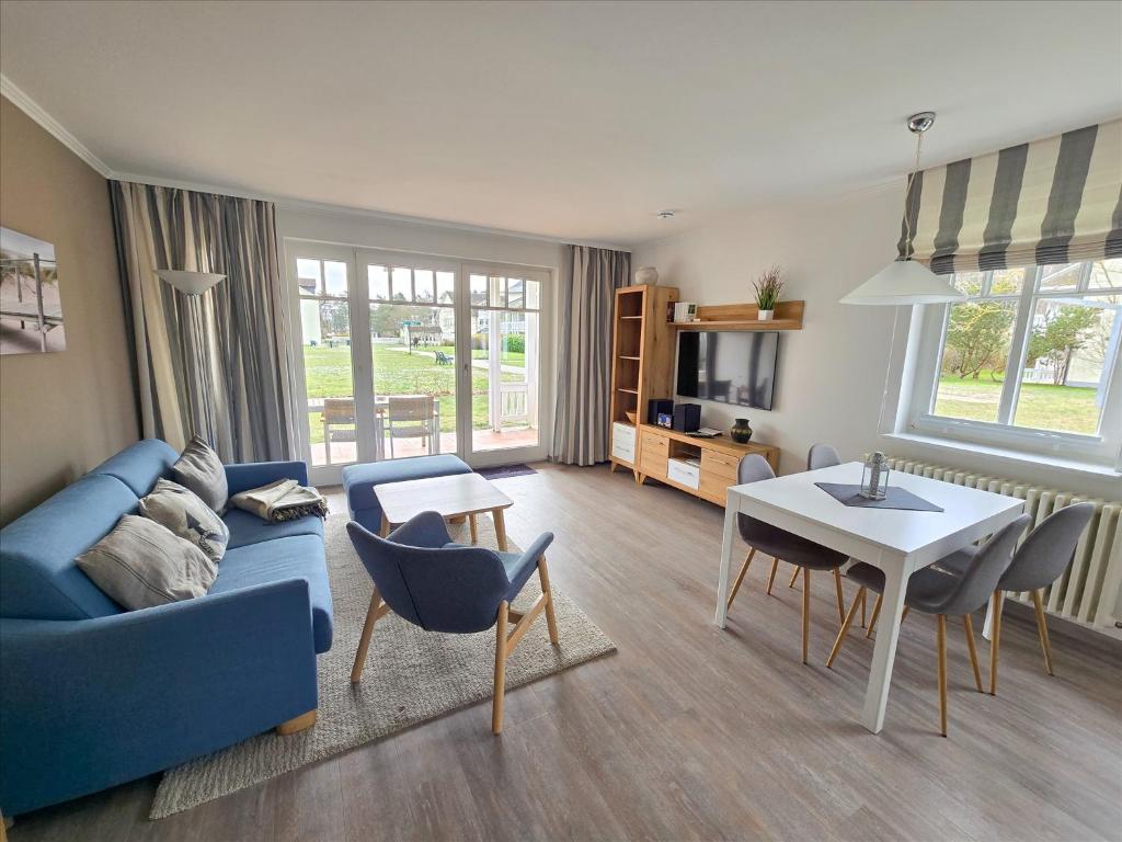 ein Wohnzimmer mit einer blauen Couch und einem Tisch in der Unterkunft Dünenpark Binz - Komfort Ferienwohnung mit 1 Schlafzimmer und Terrasse im Erdgeschoss 115 in Binz