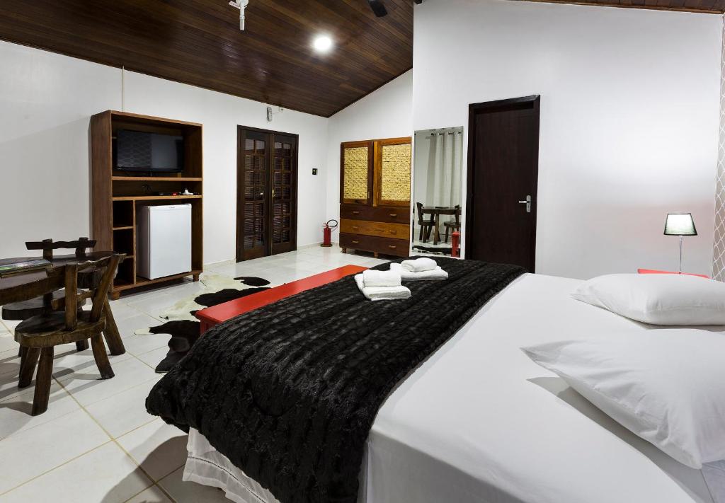 a bedroom with a large bed and a desk at Pousada Camury in Garuva