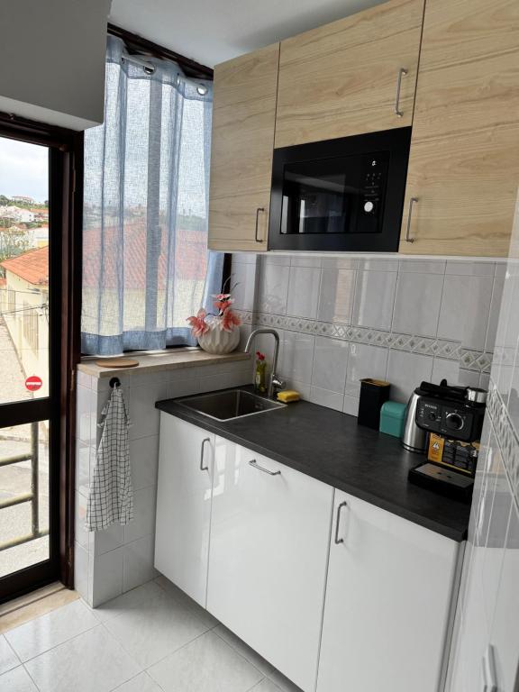 una cucina con mobili bianchi, un lavandino e una finestra di Apartman Foz Lagoon a Foz do Arelho