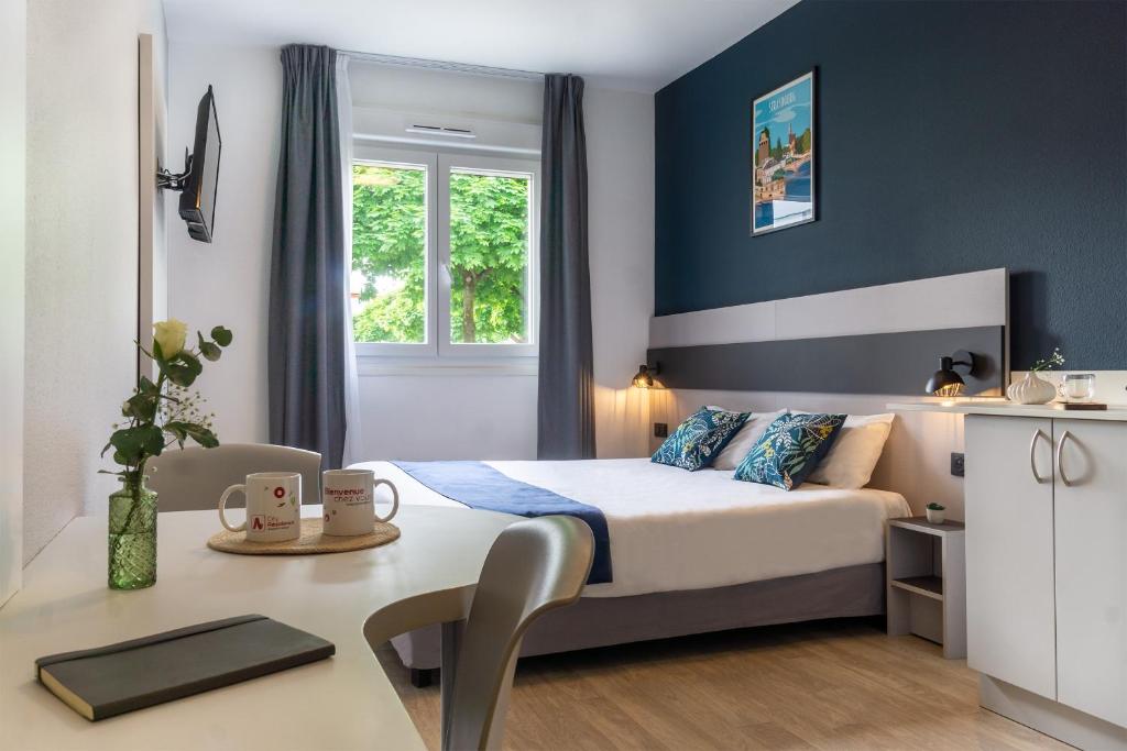 a bedroom with a bed and a desk with a table at City Résidence Strasbourg Centre in Strasbourg