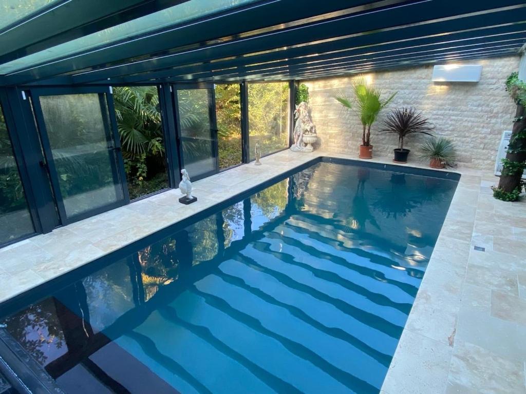 ein Pool mit blauem Wasser in einem Haus in der Unterkunft Villa riviera hammam, piscine & jacuzzi in La Ferté-Alais