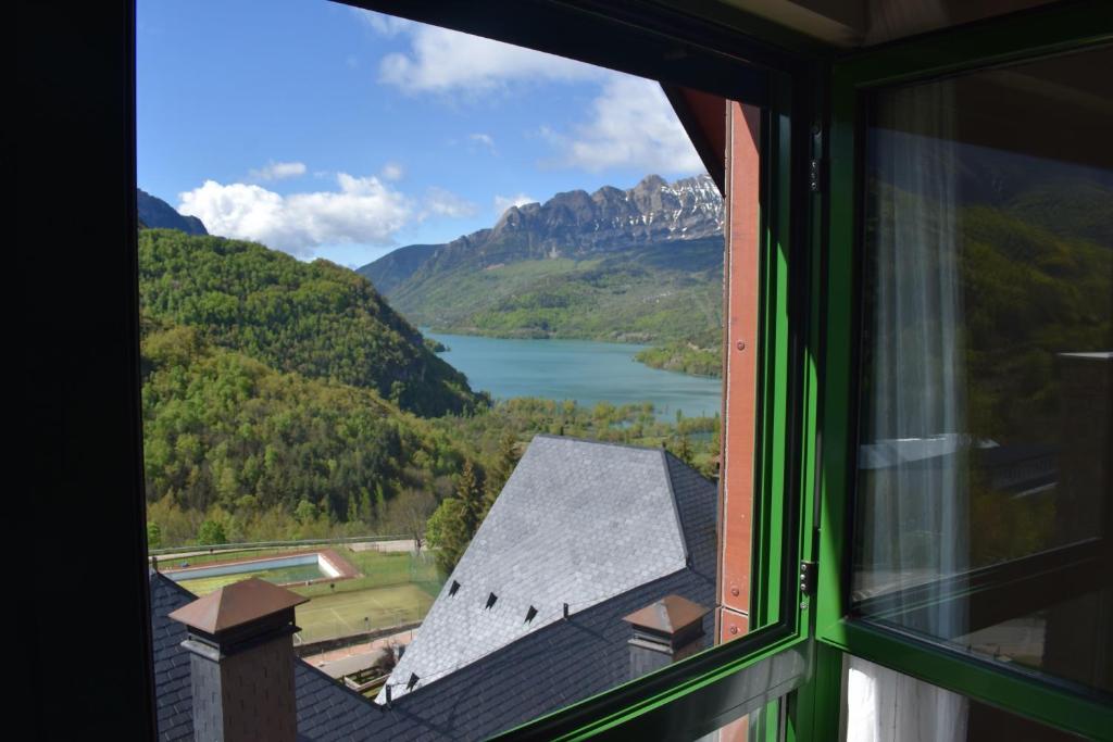 a window with a view of a lake and mountains at Argualas - Triplex con piscina - By CARDI Suites in Panticosa