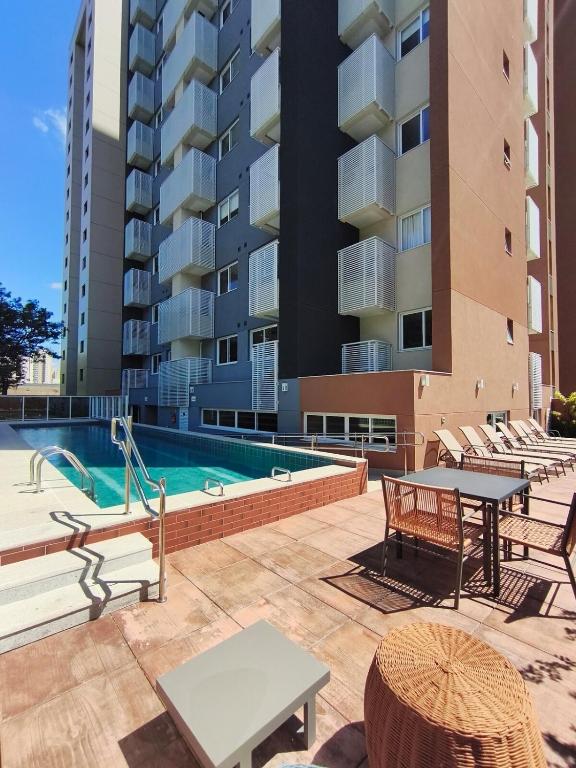 a patio with a pool and tables and a building at Studio SUPER LUXO a 5 min do Nubank Parque in São Paulo