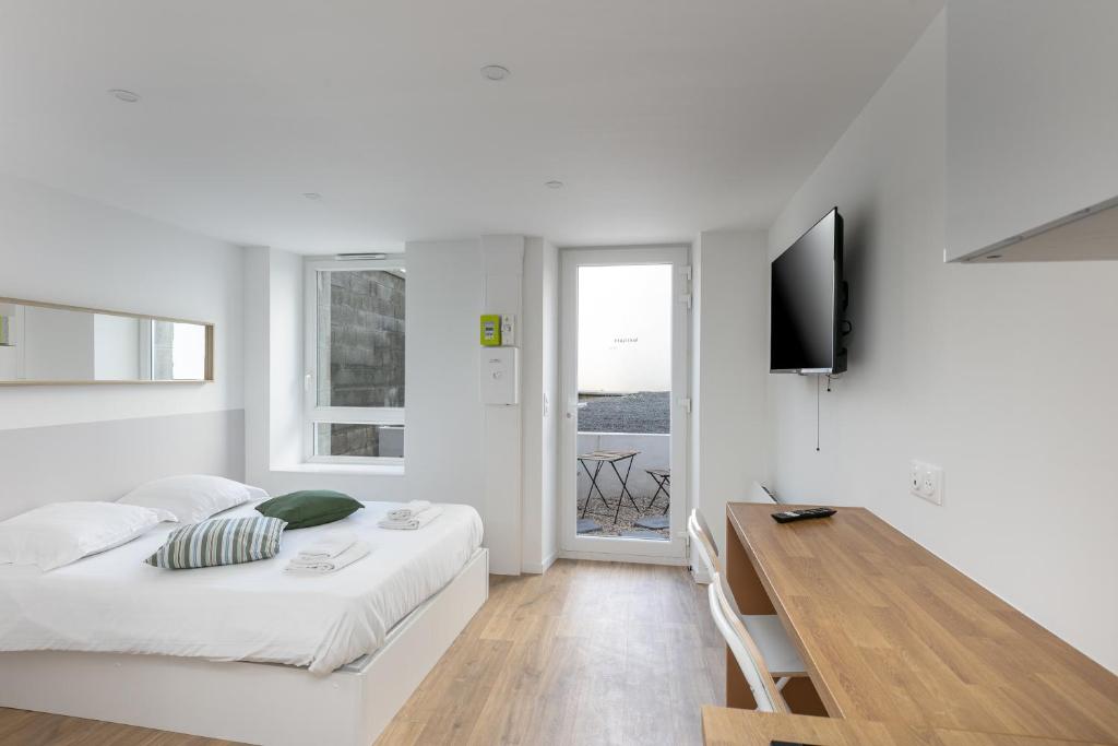 Cette chambre blanche comprend un lit et un bureau. dans l'établissement Korrigan, à Brest