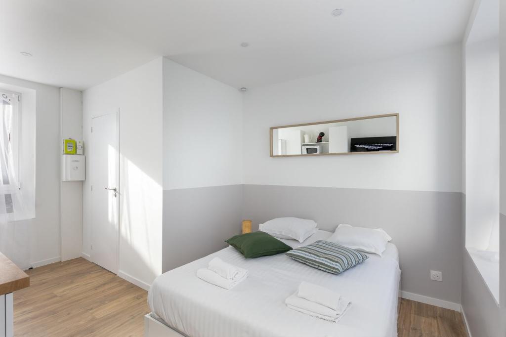 - une chambre blanche avec un lit et un miroir mural dans l'établissement Merzhin, à Brest