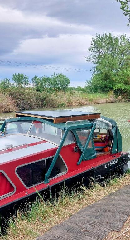 un bateau rouge garé au bord d'une rivière dans l'établissement Studio bateau au Somail, à Saint-Nazaire-dʼAude