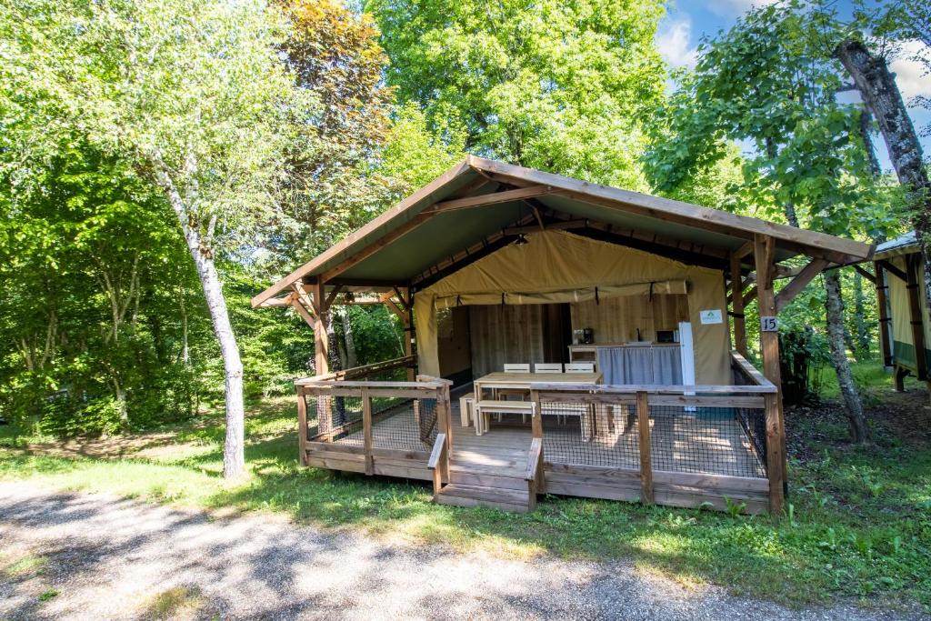 un gazebo en bois avec une terrasse dans les bois dans l'établissement Tente Lodge 2 personnes, à Saint-Martial-de-Nabirat