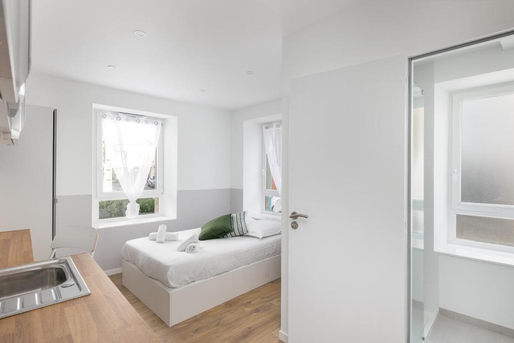 Cette chambre blanche dispose d'un lit et de deux fenêtres. dans l'établissement Ker'Ys, à Brest
