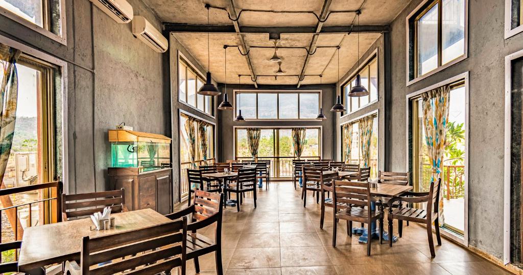 a restaurant with tables and chairs and windows at Break the Routine, Malshej in Murbād