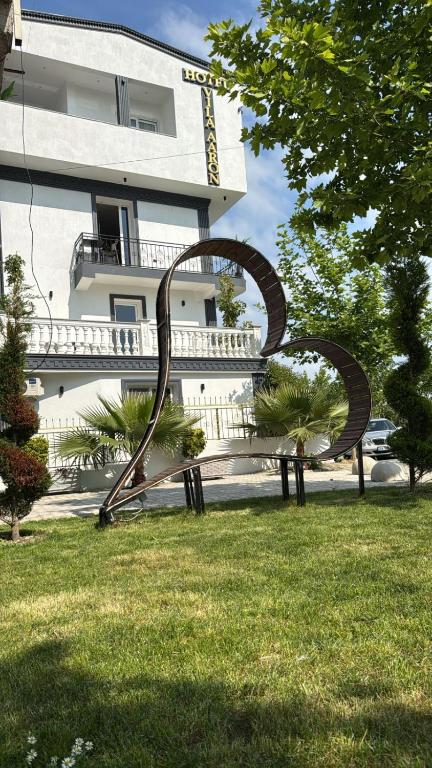 um banco de parque na relva em frente a um edifício em Hotel Vila AARON em Durrës