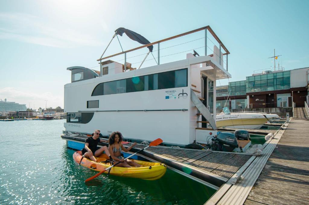 zwei Frauen in einem Kajak neben einem großen Boot in der Unterkunft Exclusivas vistas al mar en casa barco, pleno centro, terraza, parking in A Coruña