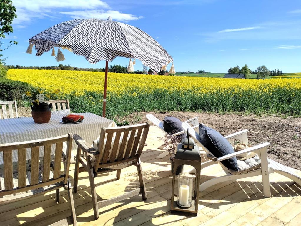 a table and chairs with an umbrella in front of a field at Towerhouse Apartment in Ystad