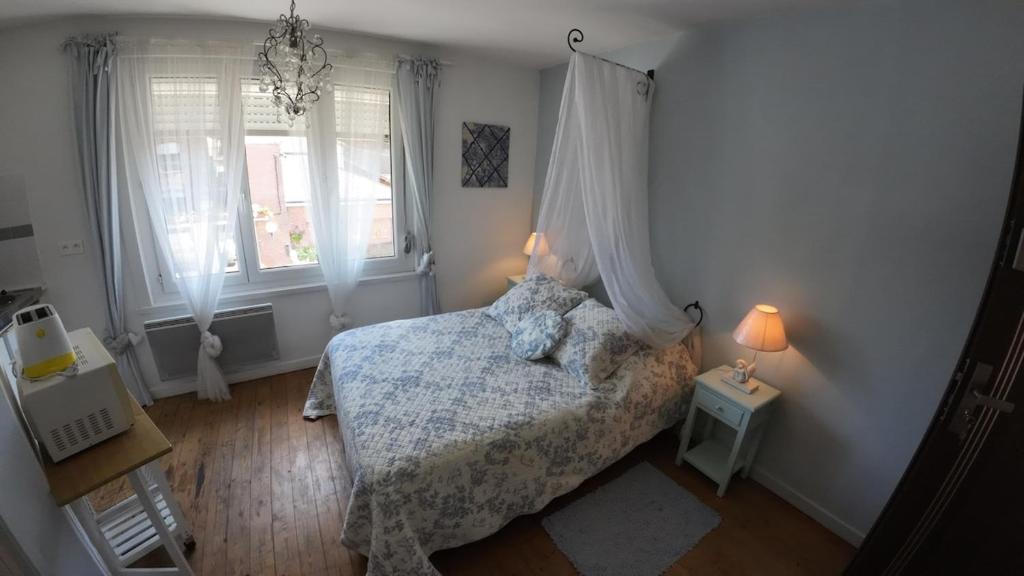 a bedroom with a bed and two windows at Studio romantique à la campagne à Mastaing in Mastaing
