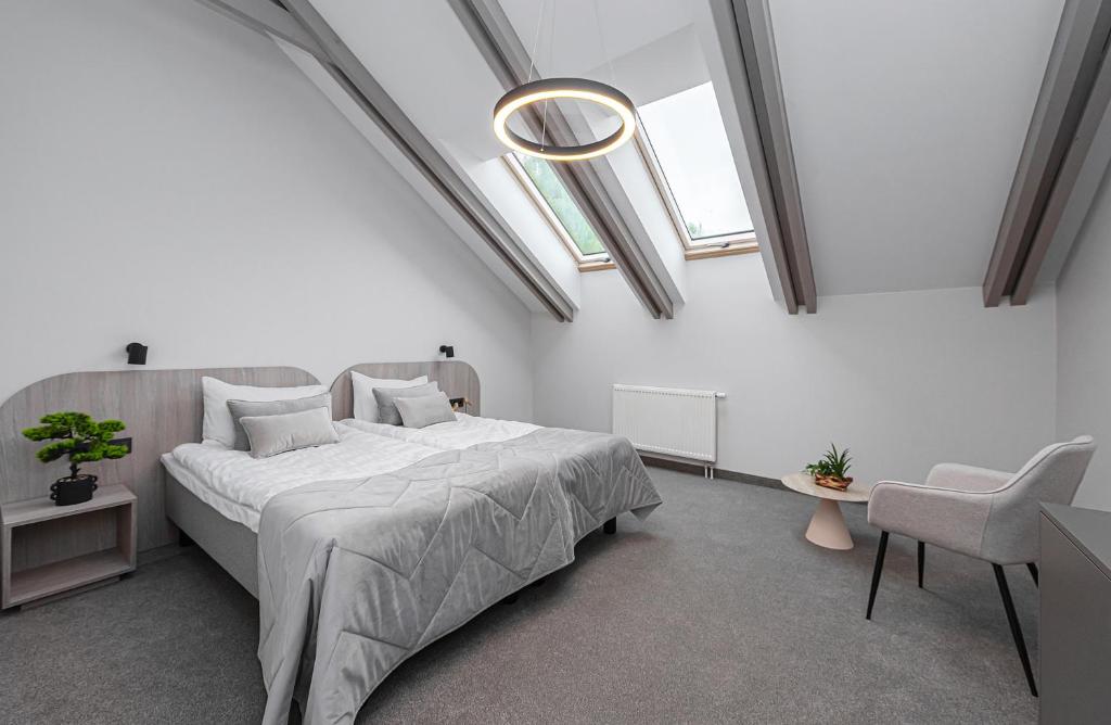 a white bedroom with a large bed and skylights at Nykščio Namai & SPA in Anykščiai