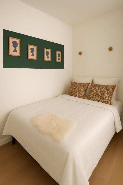 - un lit blanc dans une chambre avec des photos sur le mur dans l'établissement Grand studio neuf, lumineux et au calme ! Tout équipé - Ajaccio, à Ajaccio