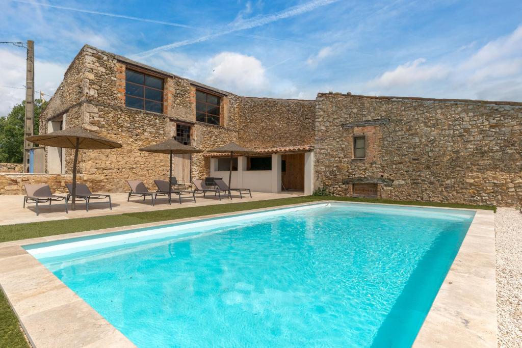 a swimming pool in front of a stone house at La Bergerie in Esparron