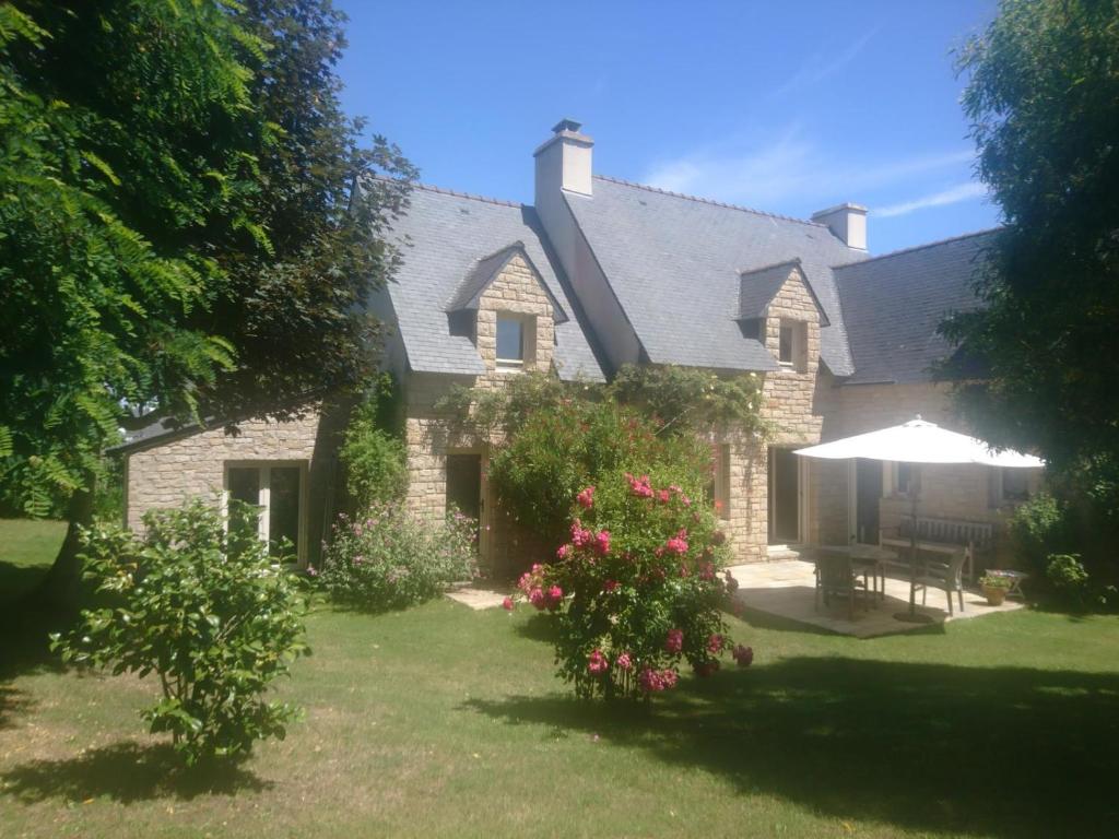une maison avec une cour fleurie et un parasol dans l'établissement Ref 010 Port-Navalo Maison pour onze personnes avec jardin, à Arzon