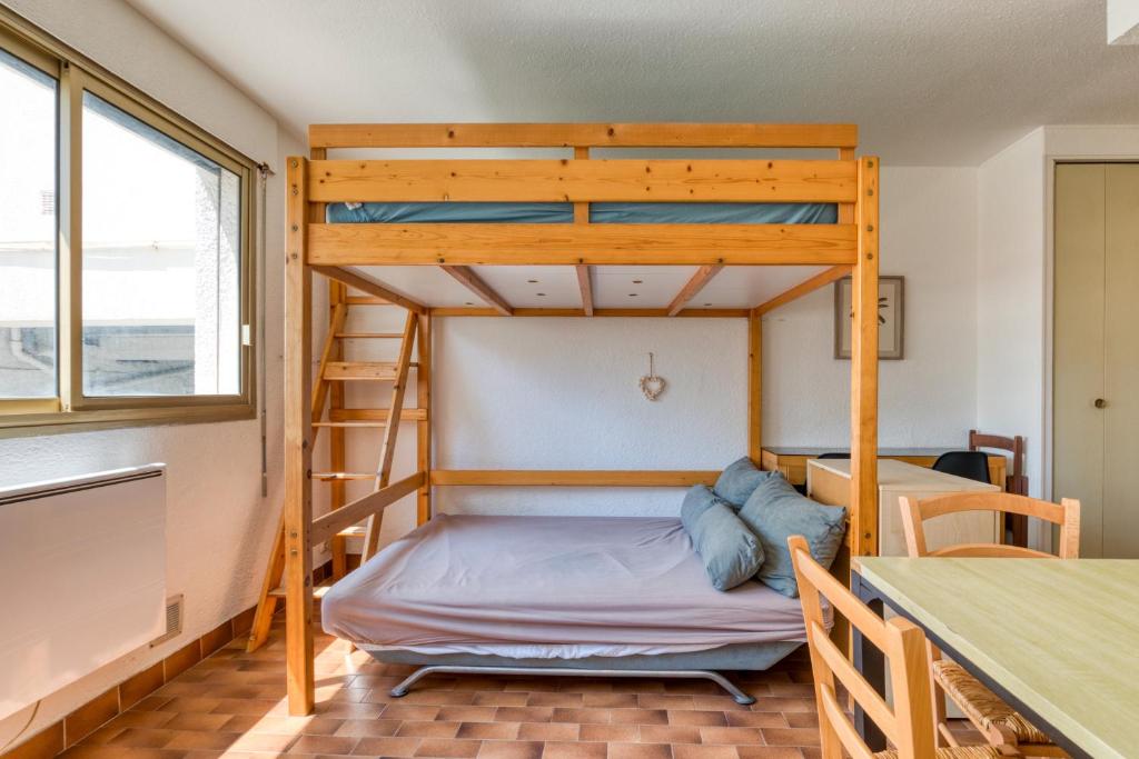 Ce lit superposé se trouve dans un dortoir doté d'une table. dans l'établissement La Grande Motte Studio, à La Grande Motte