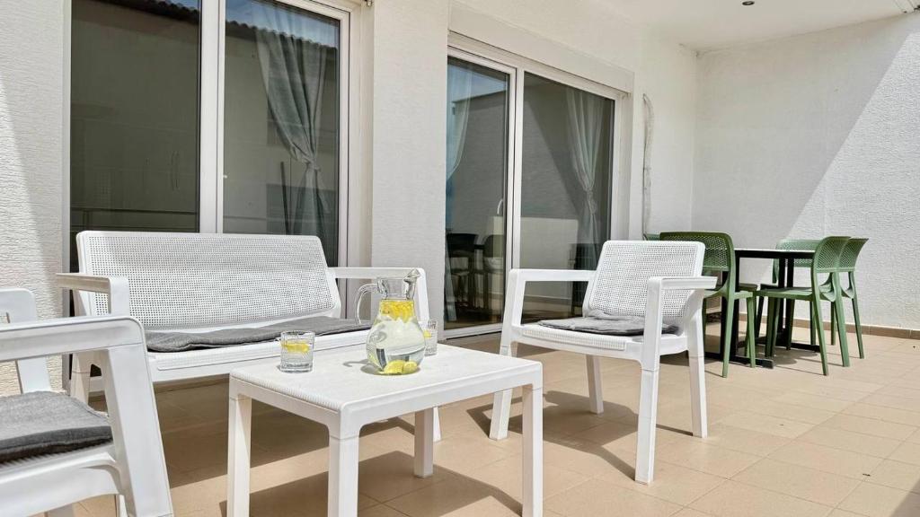 Un patio con sillas blancas y una mesa con bebidas. en Your Comfy Apartment, en Sarandë