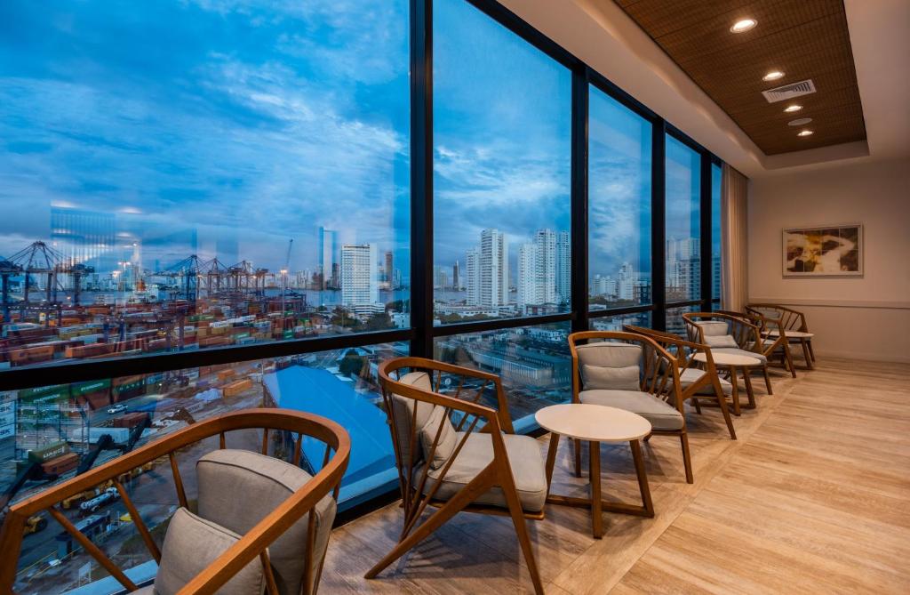 a row of chairs and tables in a room with large windows at Holiday Inn Express Cartagena Manga by IHG in Cartagena de Indias