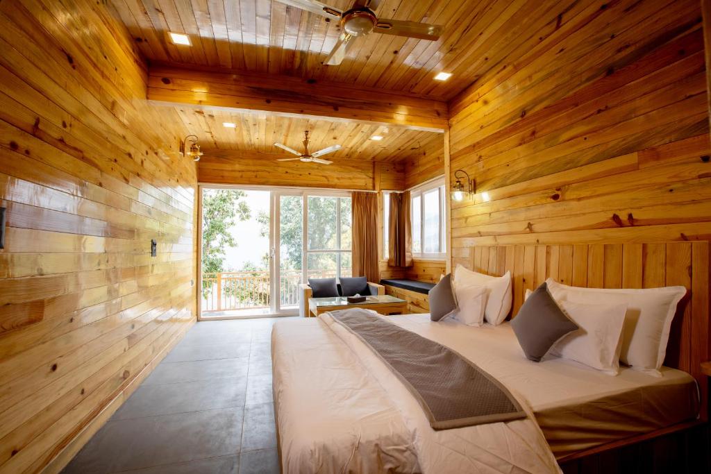 una camera da letto con un letto grande in una stanza con pareti in legno di Nirmaya Resort a Kanatal