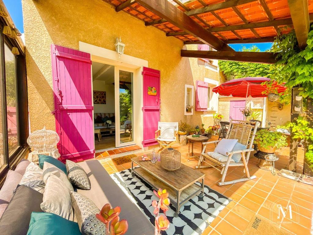 une terrasse avec un canapé, une table et un parasol dans l'établissement Maisonnette au calme avec jardin cosy à Sanary, à Sanary-sur-Mer