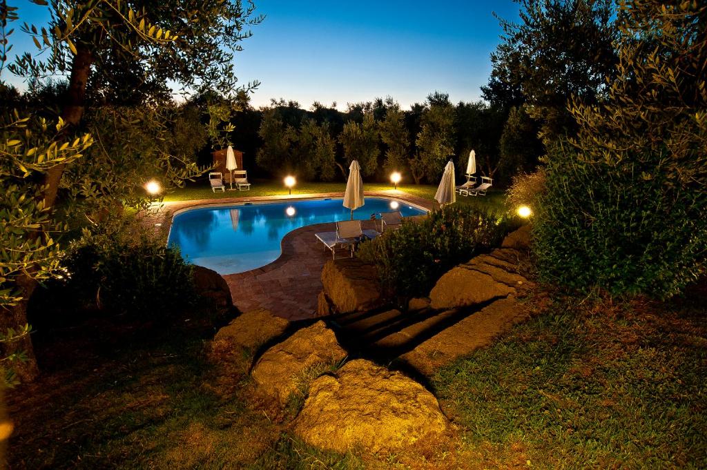 a swimming pool with umbrellas in a yard at night at Cerchio Verde in Pitigliano