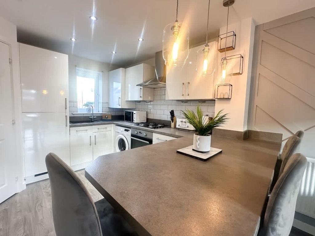 a kitchen with a table and chairs and a kitchen with white cabinets at Ruby Place by Blue Skies Stays in Hartlepool