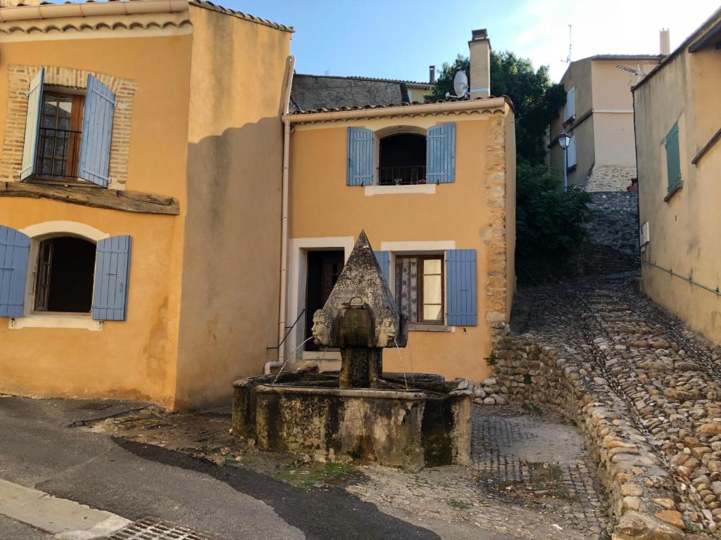 une vieille maison avec une statue dans la rue dans l'établissement Maison de la Fontaine, à Saint-Roman-de-Malegarde