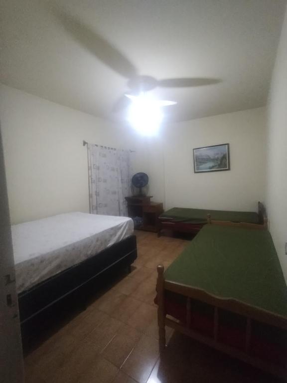 a bedroom with two beds and a ceiling fan at Apto Aconchegante Praia Grande in Praia Grande