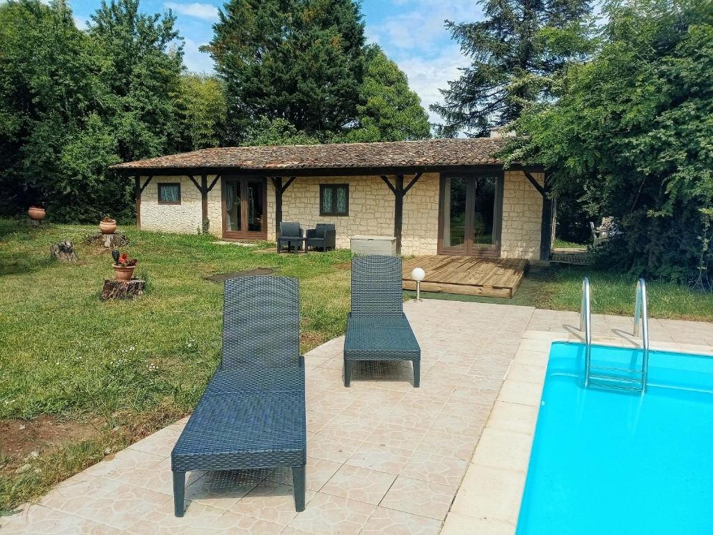 two chairs and a pool in front of a house at Quatre Saisons Été in Bergerac