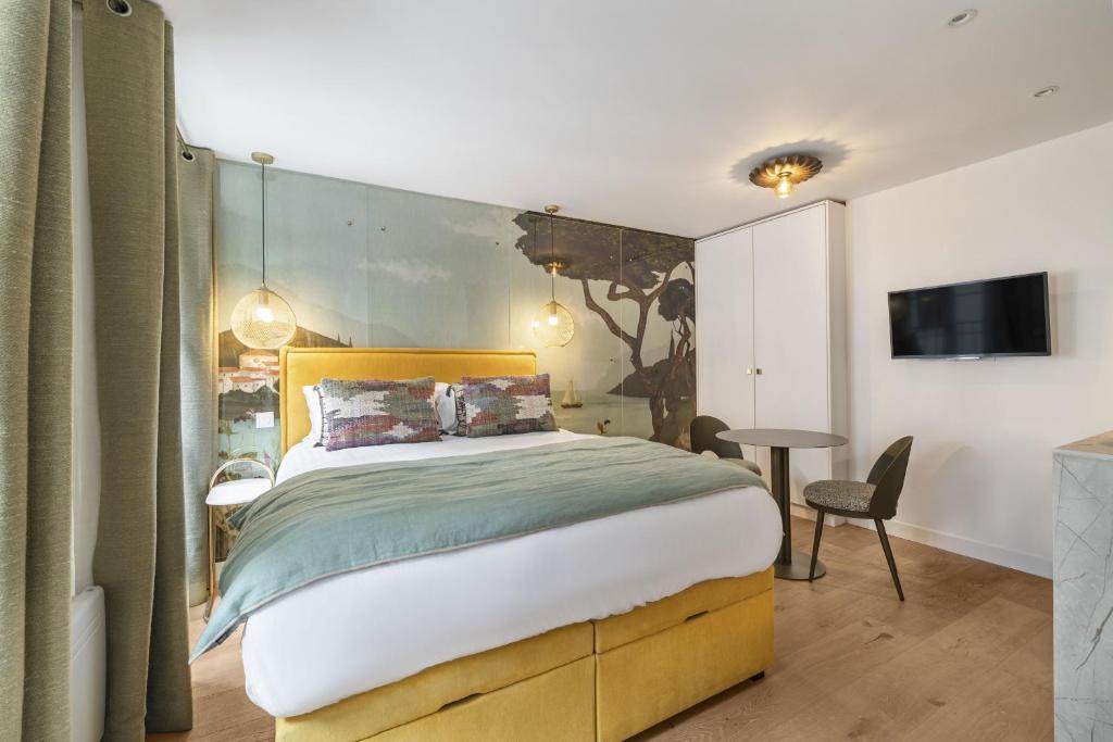 - une chambre avec un grand lit et une tête de lit jaune dans l'établissement Petito, à Paris