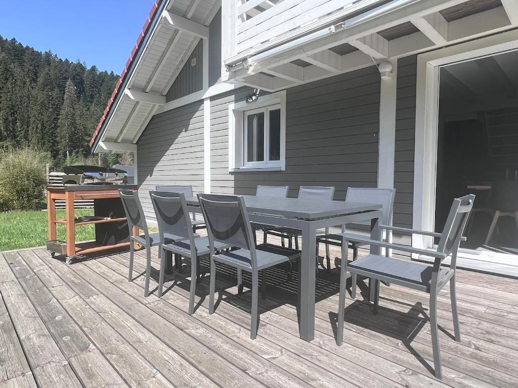 un patio avec une table et des chaises sur une terrasse dans l'établissement Le Vertpheny, Chalet calme et coszy à 500 m du lac, à Gérardmer