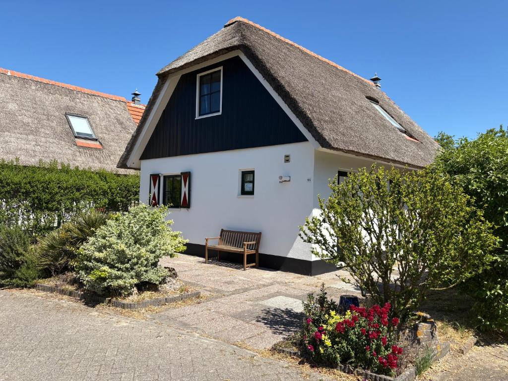 a white and black house with a thatched roof at Buitenplaats 105 in Callantsoog