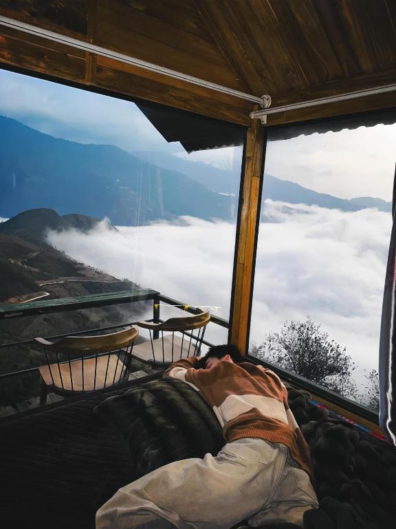 a bed in a room with a view of the clouds at Tà Xùa Retreat Khu Nghỉ Dưỡng in Bắc Yên