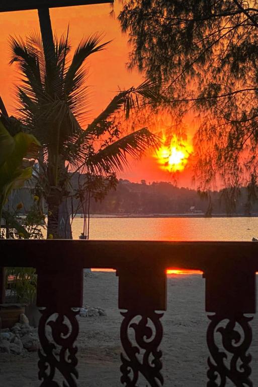 a sunset over a body of water with a palm tree at Colibri Beach Resort in Chaloklum