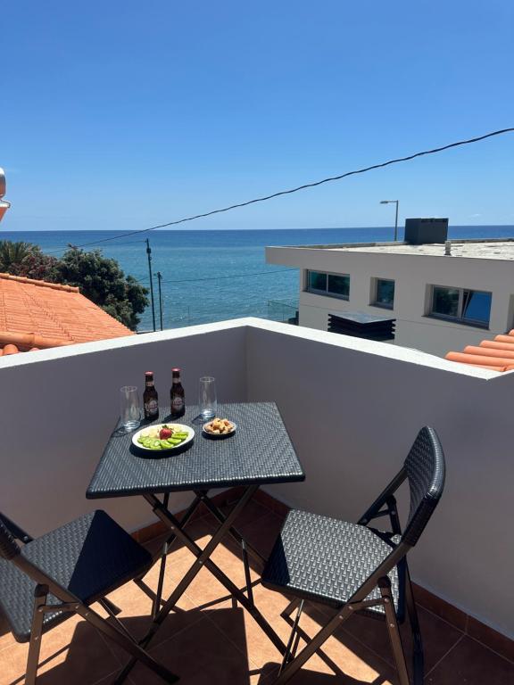 a table and chairs on a balcony with the ocean at Gori House in Madalena do Mar