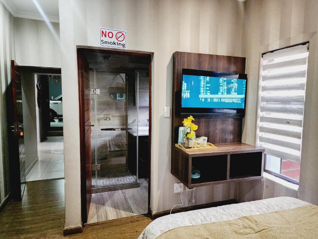 a room with a nox sign and a bed and a television at The Green leaf Executive Home in Pretoria