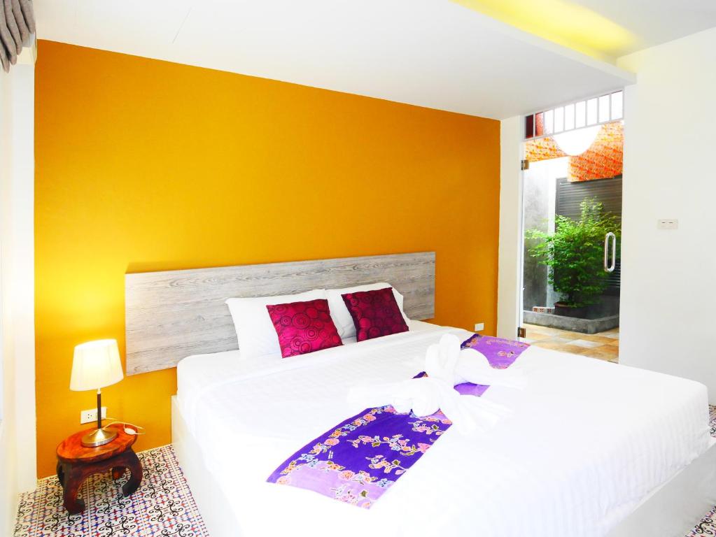 1 dormitorio con cama blanca y pared amarilla en Forest Bungalows & Mama's Restaurant, en Chalong 