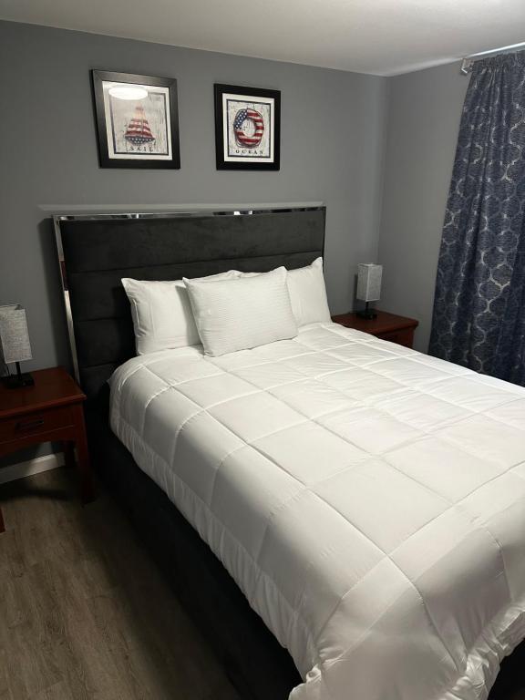 ein großes weißes Bett in einem Schlafzimmer mit 2 Tischen in der Unterkunft Atlantic Breeze Motel &amp; Apartments in Ocean City