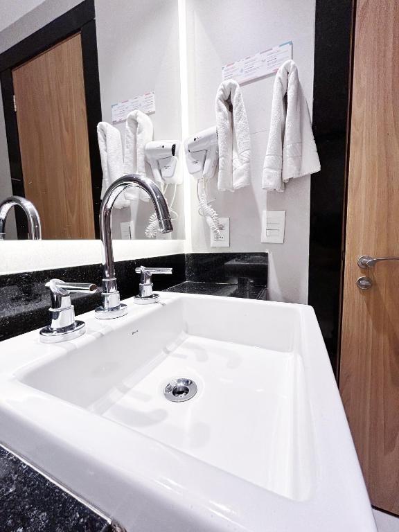 a bathroom with a sink and towels hanging on the wall at Mar Ipanema Hotel in Rio de Janeiro